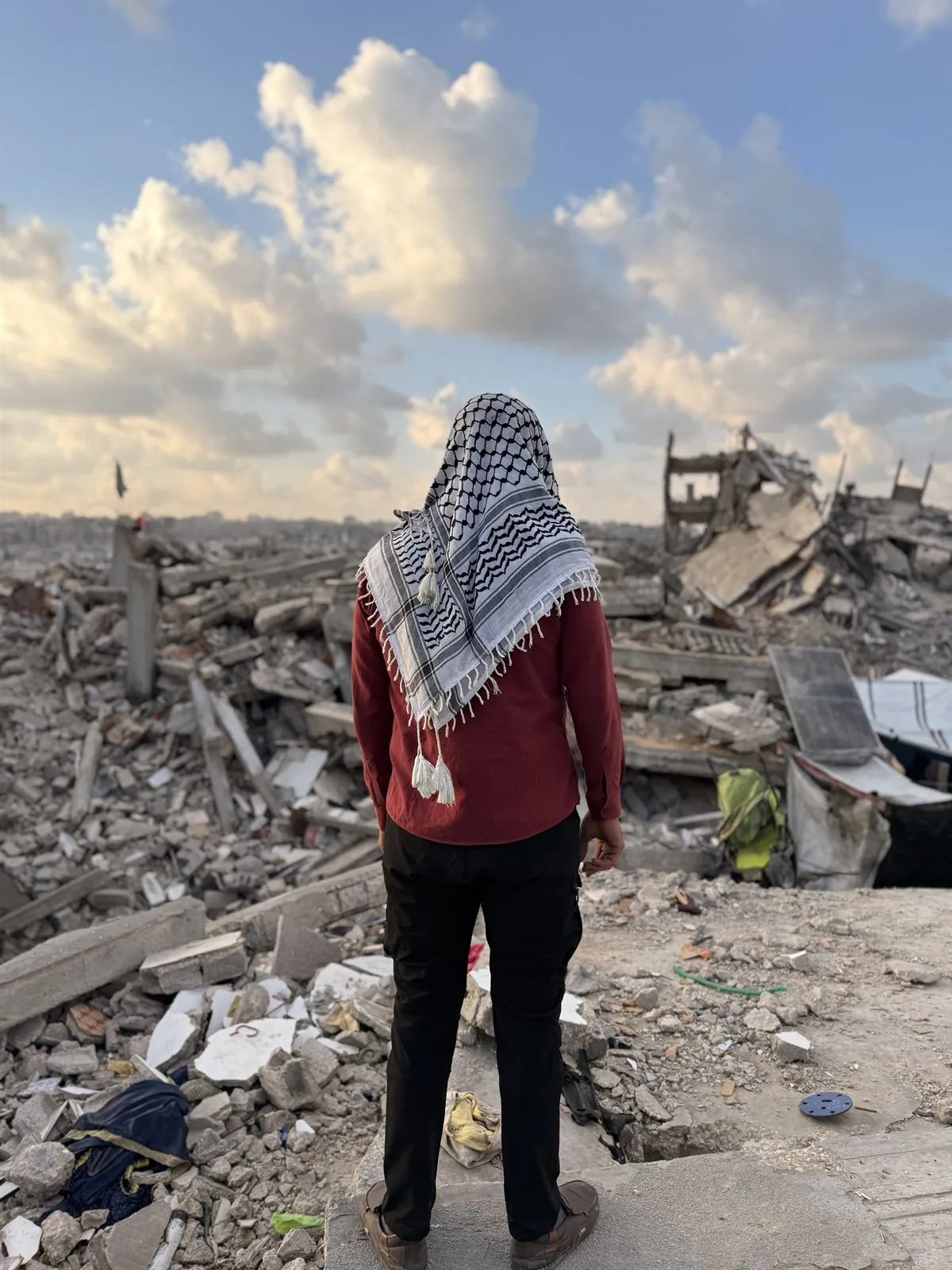 شخصية جود بالكوفية الفلسطينية تقف أمام آثار الدمار في غزة